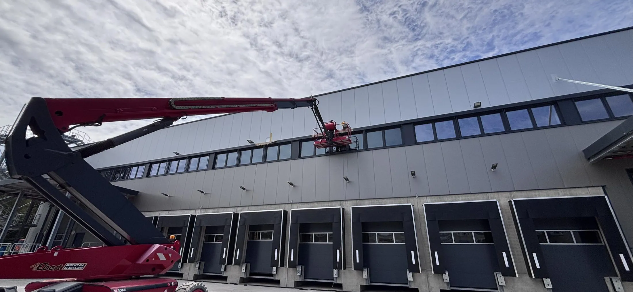 Arbeitsbühne vor einer Industrie- und Logistikhalle.